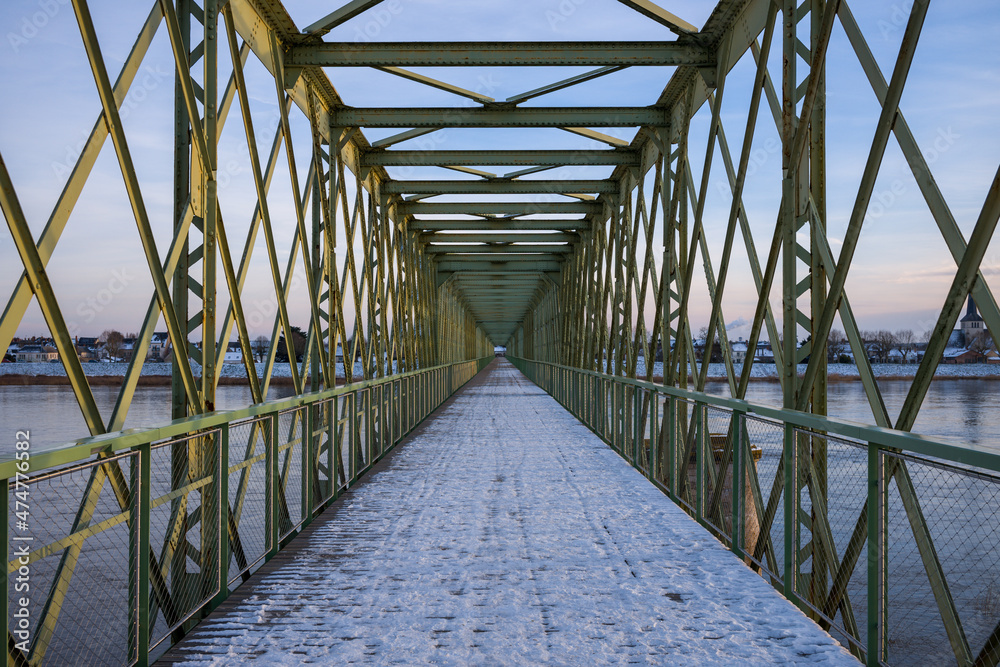 The pedestrian bridge of Sully sur Loire under the snow in Europe, in France, in the Center region, in the Loiret, towards Orleans, in Winter, during a sunny day.