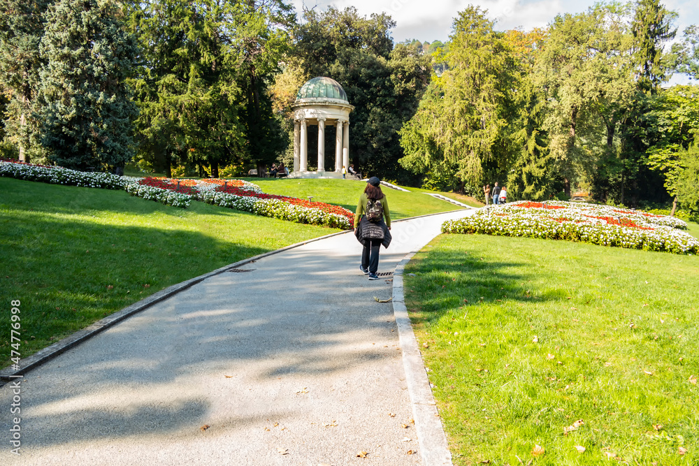 Woman walking in a green park with flowers. October 2021 Como, Lombardy - Italy
