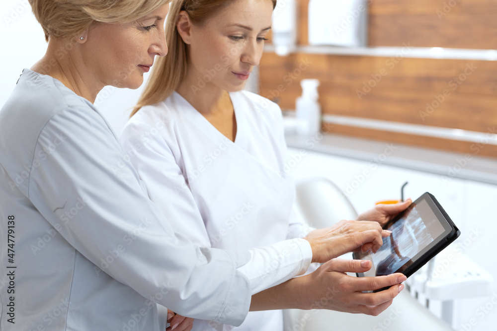 Two professional dentists checking x ray picture on digital tablet Two professional dentists checking x ray picture on digital tablet