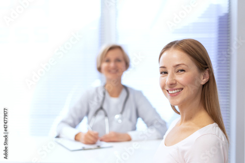 Happy patient sitting against doctor on blurred background