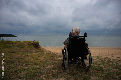 Elderly grandmother sits in a wheelchair by the sea