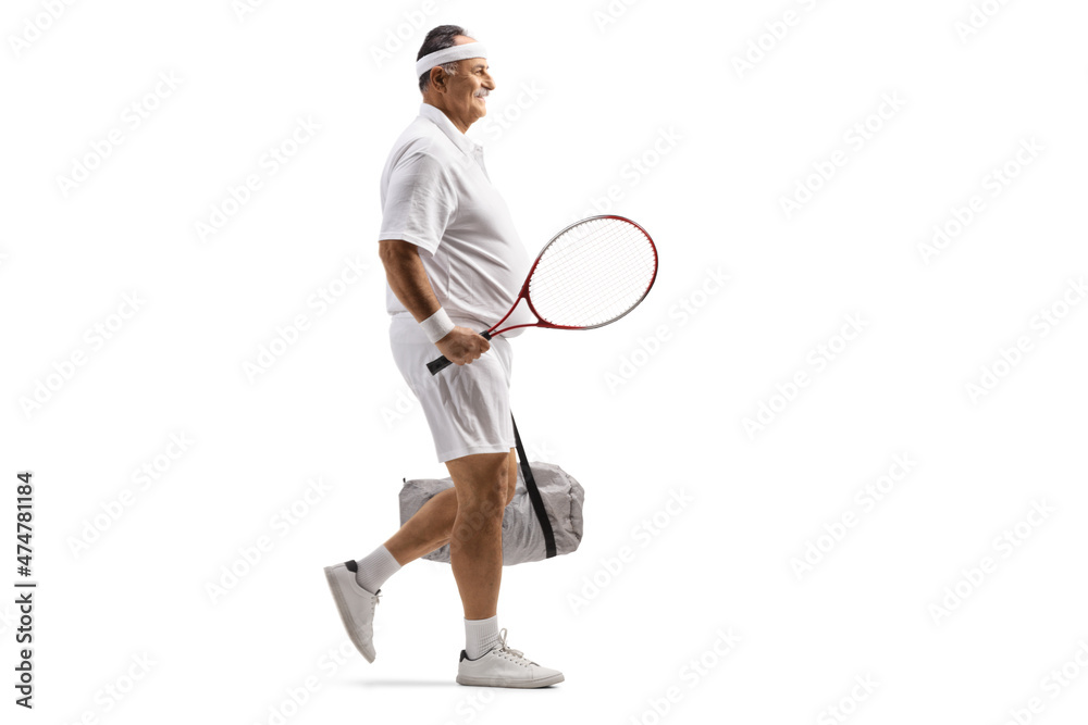 Full length profile shot of a mature male tennis player walking with a sports bag Full length profile shot of a mature male tennis player walking with a sports bag