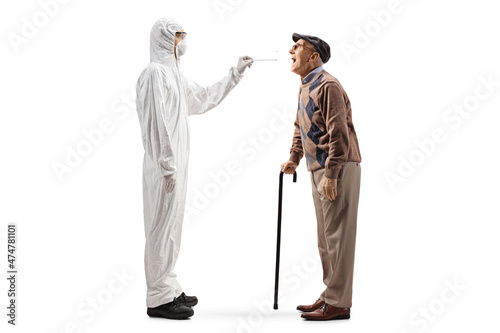 Full length profile shot of an epidemiologist in a hazmat suit taking a cotton swab test from an elderly man