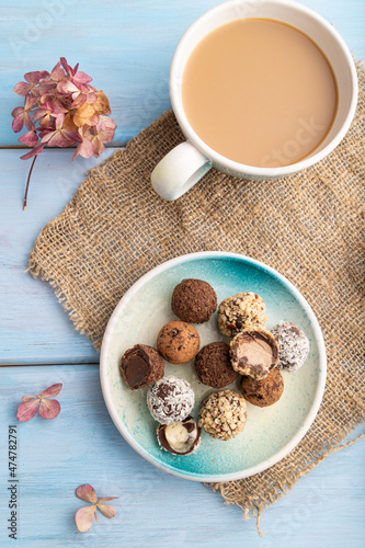 Chocolate truffle candies with cup of coffee on a blue wooden background. top view, close up.