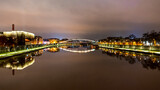 Wieczorne ujecie rzeki Wisła w centrum Krakowa z oświetlonymi budynkami po jej brzegach