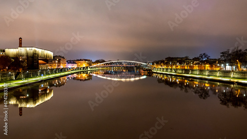 Wieczorne ujecie rzeki Wisła w centrum Krakowa z oświetlonymi budynkami po jej brzegach