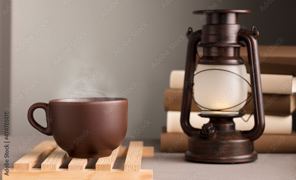 brown cup of coffee with hot steam, on desk with sunlight lamp, grey background