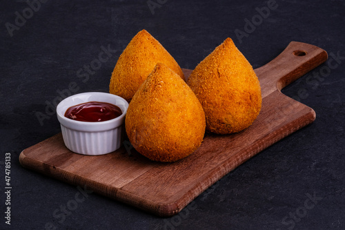 traditional fried coxinha on a wooden board over slate stone