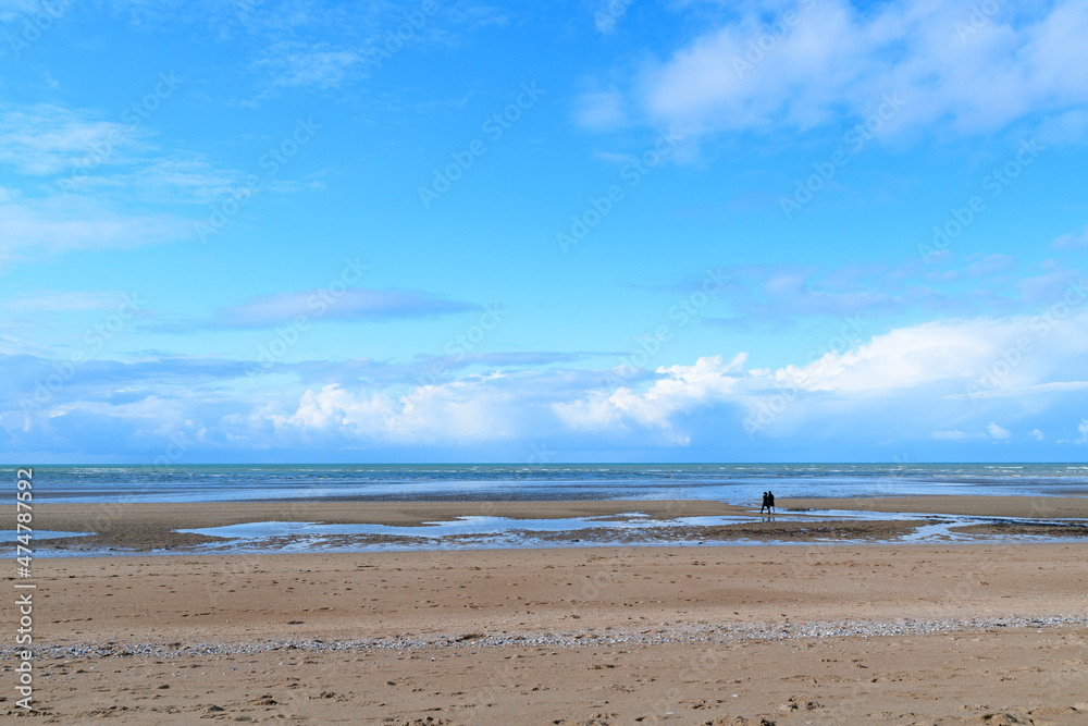 The fine sand beach in front of the Channel Sea under the clouds in Europe, France, Normandy, Ouistreham, in summer, on a sunny day. The fine sand beach in front of the Channel Sea under the clouds in Europe, France, Normandy, Ouistreham, in summer, on a sunny day.