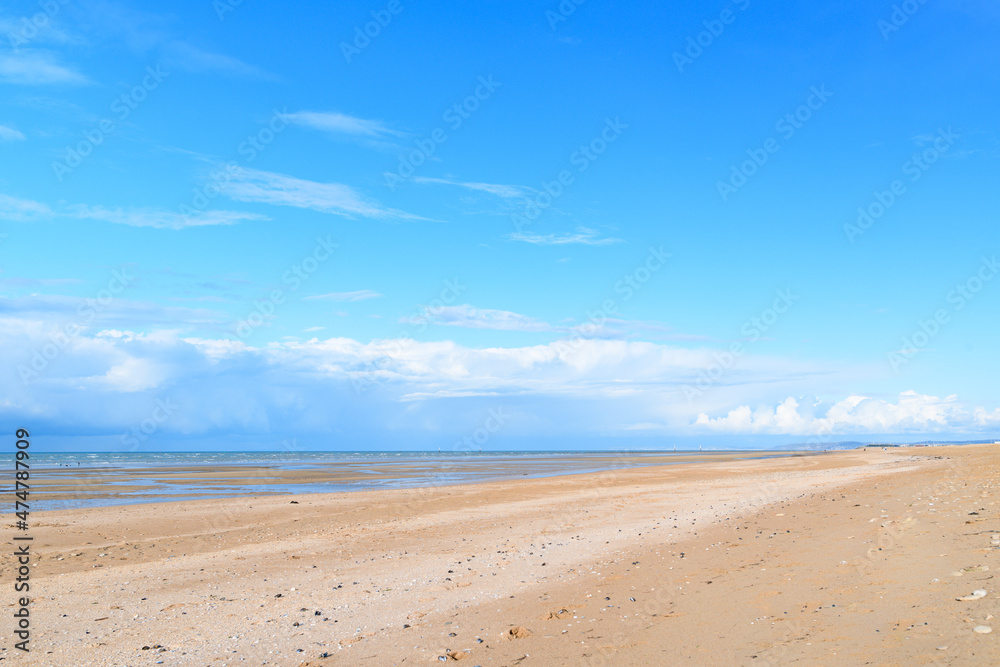 The long sandy beach by the Channel Sea in Europe, France, Normandy, Ouistreham, in summer on a sunny day.