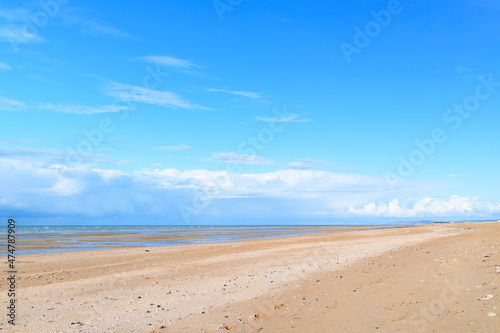 The long sandy beach by the Channel Sea in Europe, France, Normandy, Ouistreham, in summer on a sunny day.