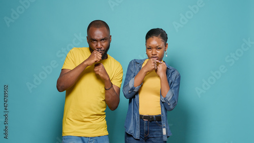 African american couple punching air with fists in front of camera. Man and woman throwing punches and preparing for boxing fight together, doing demostration exercise with knuckles. photo