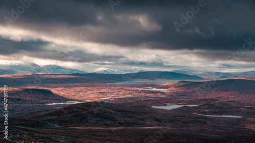 Landscape of Pieljekaise National Park in autumn with lakes and mountains in Lapland in Sweden, colored plants, dramatic light and clouds in sky. photo