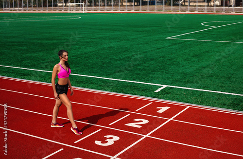 Ready, Set, Go. Young athletic fit hot healthy woman at the sports track at the stadium is about to run a race at the running competition.