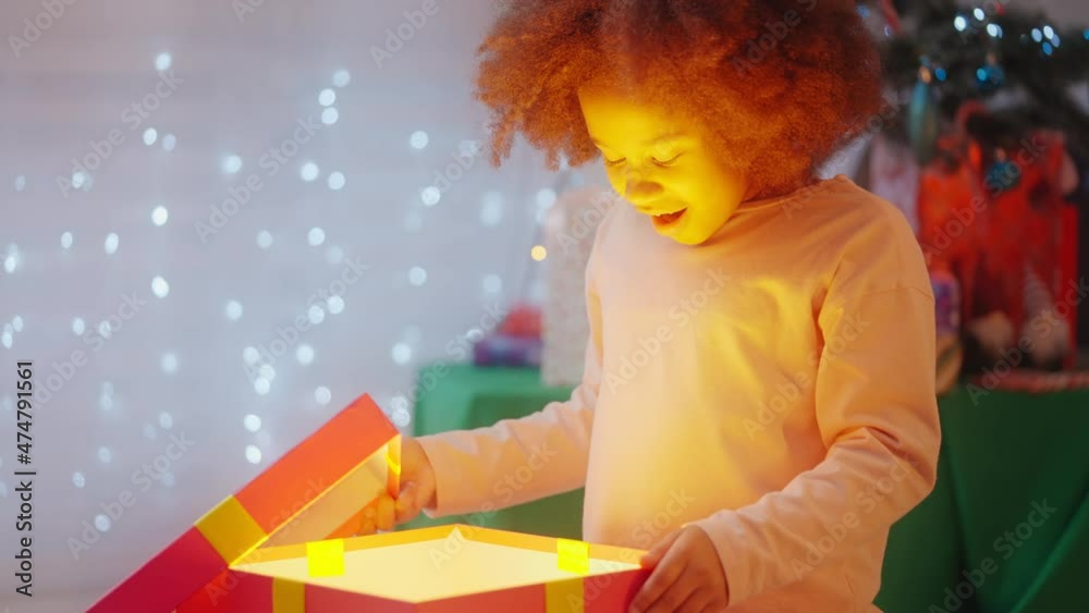 Cute little girl opening Christmas present and surprised to see what's inside