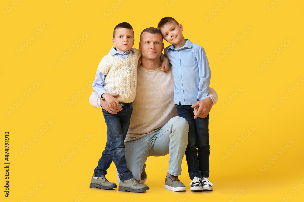 Portrait of father with little children on yellow background Portrait of father with little children on yellow background