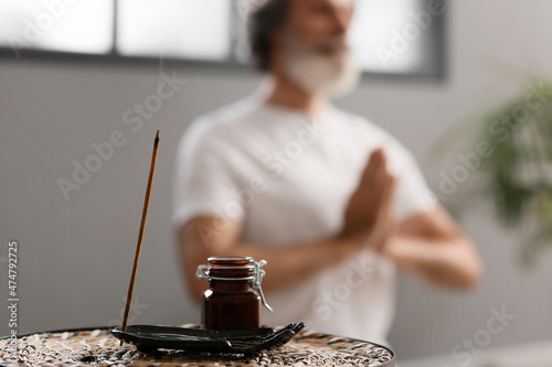 Incense stick and essential oil on table of meditating man photo