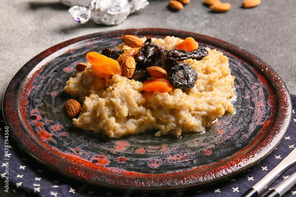 Tasty oatmeal with prunes, dried apricots and almond nuts in plate on