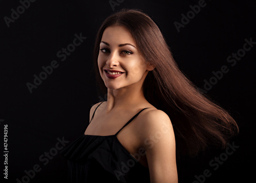 Beautiful makeup woman with long hair in action looking happy on black background. Closeup portrait of natural happiness.