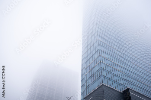 Business center in the tower skyscraper in the financial downtown center of the city in the foggy misty day with cover by clouds tops. Financial business abstract architecture concept.