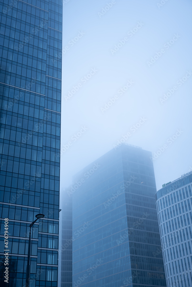 Business center in the tower skyscraper in the financial downtown center of the city in the foggy misty day with cover by clouds tops. Financial business abstract architecture concept.
