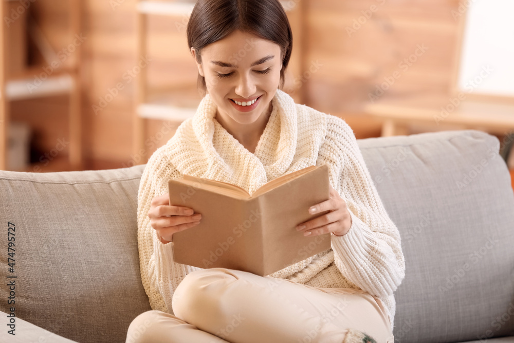Beautiful young woman reading book on sofa at home Beautiful young woman reading book on sofa at home