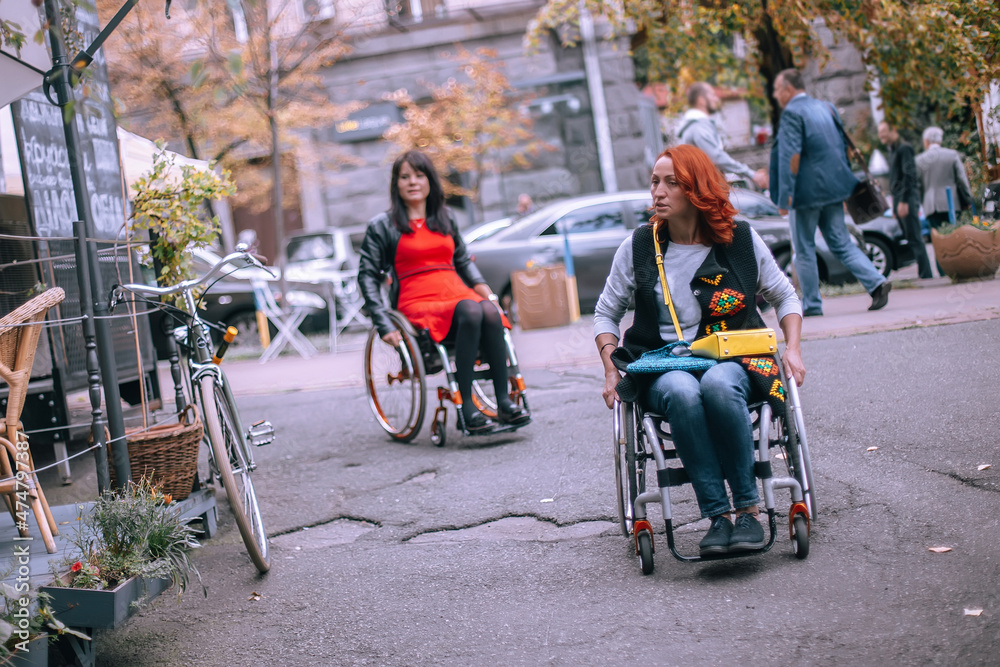 Obraz premium Girls in wheelchairs choose cafe accessible to people with special needs. Freedom of movement of persons with special needs