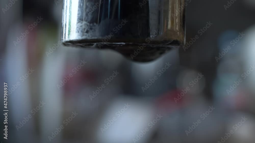 Macro Close Up Of Slow Drip From End Of Tap With Bokeh Background. Locked Off Macro Close Up Of Slow Drip From End Of Tap With Bokeh Background. Locked Off