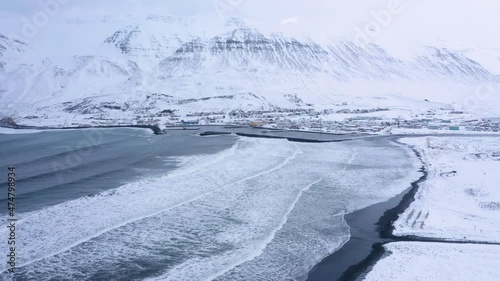 Aerial View Of Olafsfjordur Fishing Town In North Iceland, Revealing Fish Racks On The Snowy Shore In Early Winter. drone pullback photo