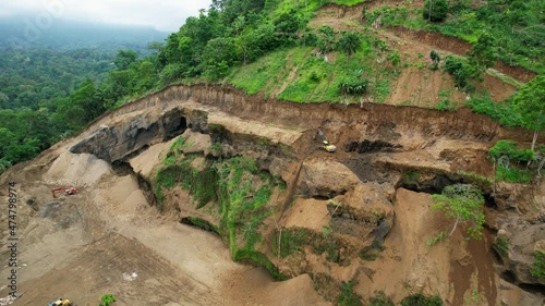 Aerial view of digger cleaning destruction of a jungle landslip - orbit, drone shot photo