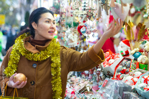 Portrait of happy asian woman choosing Christmas toys at Christmas market