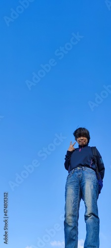 The girl in a jump. Young beautiful woman posing against blue sky bright sunny weather
