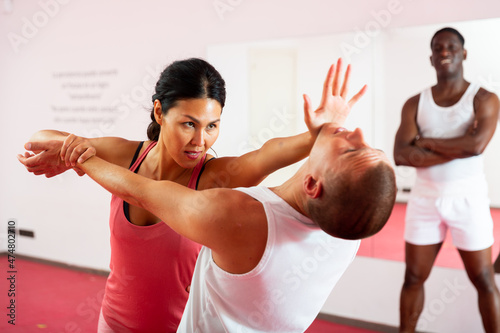 Active woman with professional trainer are training captures on the self-defense course