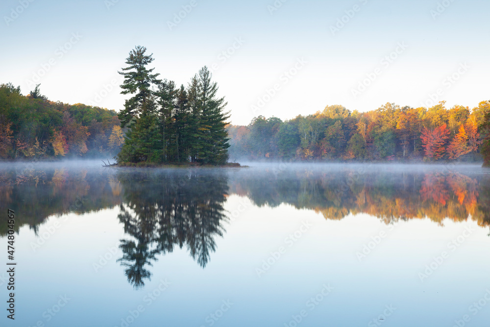 Beautiful calm lake with trees in autumn color and a small island in northern Minnesota at dawn - obrazy, fototapety, plakaty 