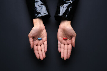 Hands with blue and red pills on dark background. Concept of choice