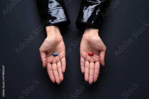 Hands with blue and red pills on dark background. Concept of choice