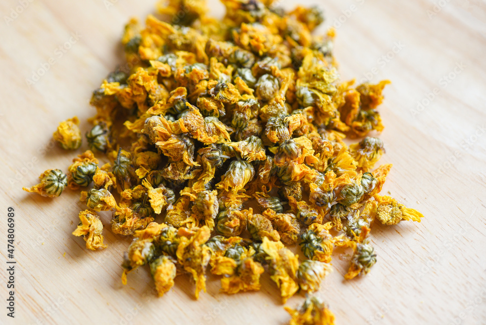 Dried chrysanthemum buds for herbal tea on wooden background, dry chrysanthemum flower yellow Dried chrysanthemum buds for herbal tea on wooden background, dry chrysanthemum flower yellow