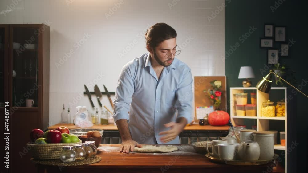 Young man chef cooking pies, making dough. Spanish husband preparing family breakfast in cozy kitchen. Latin american guy, handsome cook close-up.