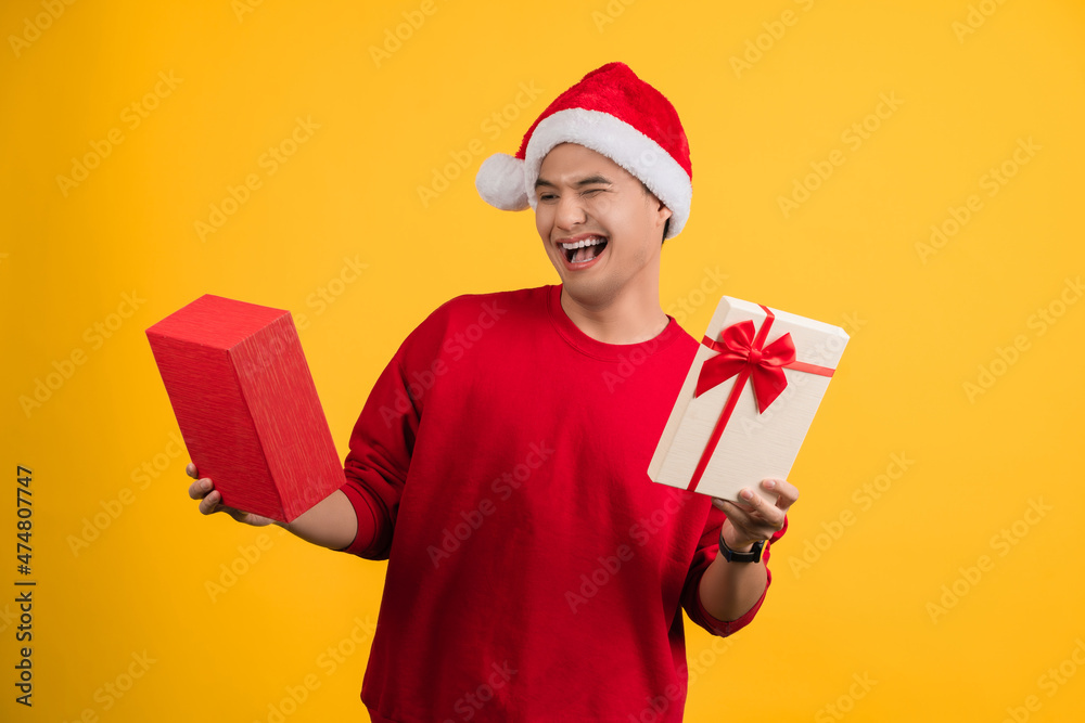 Happy asian man holding a gift box on christmas new year on a yellow background isolated Man receives a gift from Santa Claus. Happy asian man holding a gift box on christmas new year on a yellow background isolated Man receives a gift from Santa Claus.