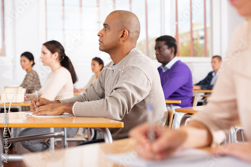 Free Download Portrait of focused young adult male studying in classroom with colleagues - GFXLoad