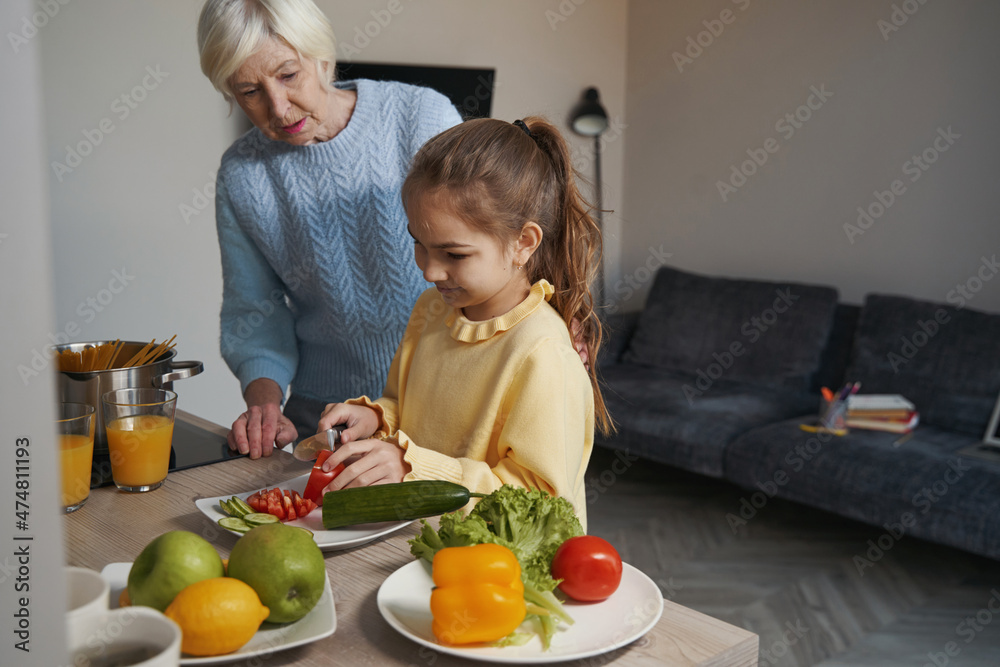 Caring grandmother passing on kitchen skills to her lovely granddaughter