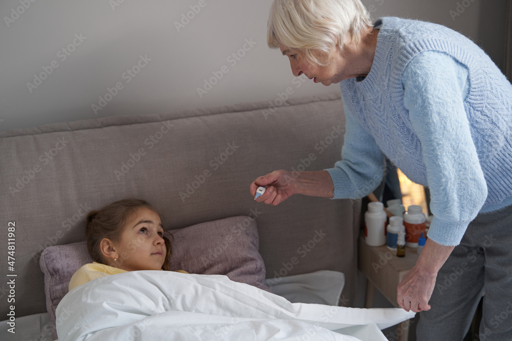 Little girl in bed being tended to by her caring grandmother
