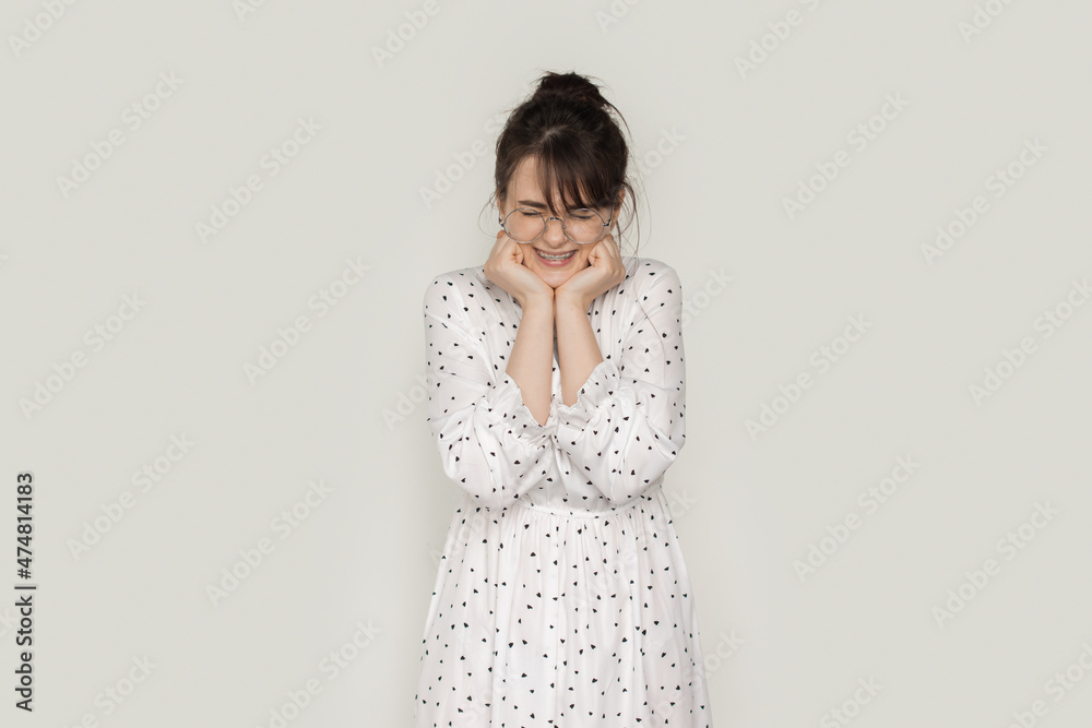 Portrait of an excited young woman screaming and holding her hands under chin isolated over white background Portrait of an excited young woman screaming and holding her hands under chin isolated over white background