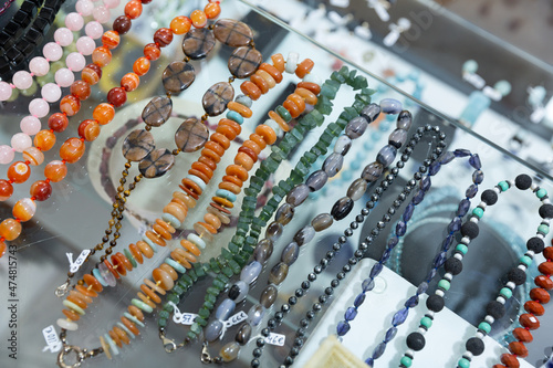 Variety of necklaces and beads from semiprecious stones offered for sale in showcase of shop