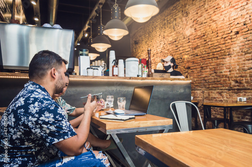 young latin male and female couple freelancers working in a restaurant with a computer