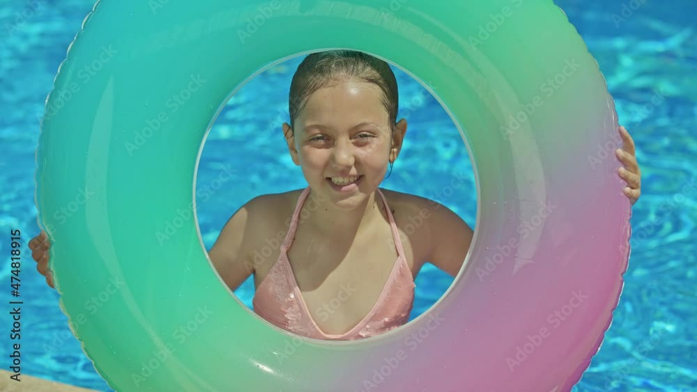 Little girl in swimsuit with inflatable rubber ring in swimming pool ...
