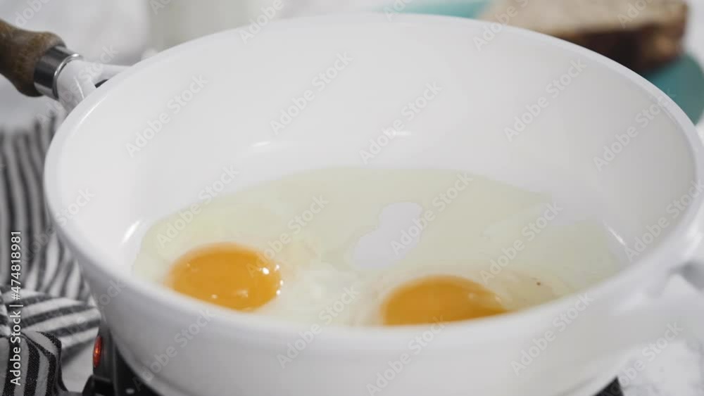 Close up view. Frying farm fresh eggs in a white skillet. Close up view. Frying farm fresh eggs in a white skillet.