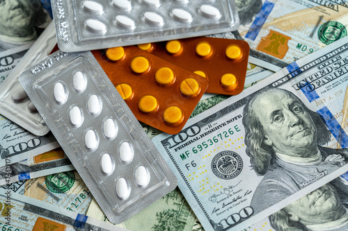 Pill blisters on 100 dollar bills. Image alluding to the relationship between health and money.