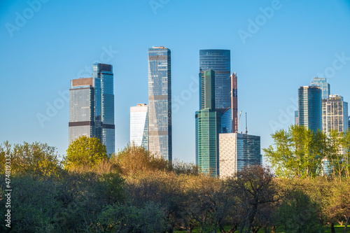 Green trees on background modern skyscrapers in the Moscow city. Panorama of new Moscow City buildings in spring