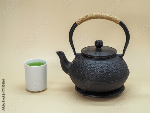 Cup of Fresh Green Tea with Black Cast Iron Teapot